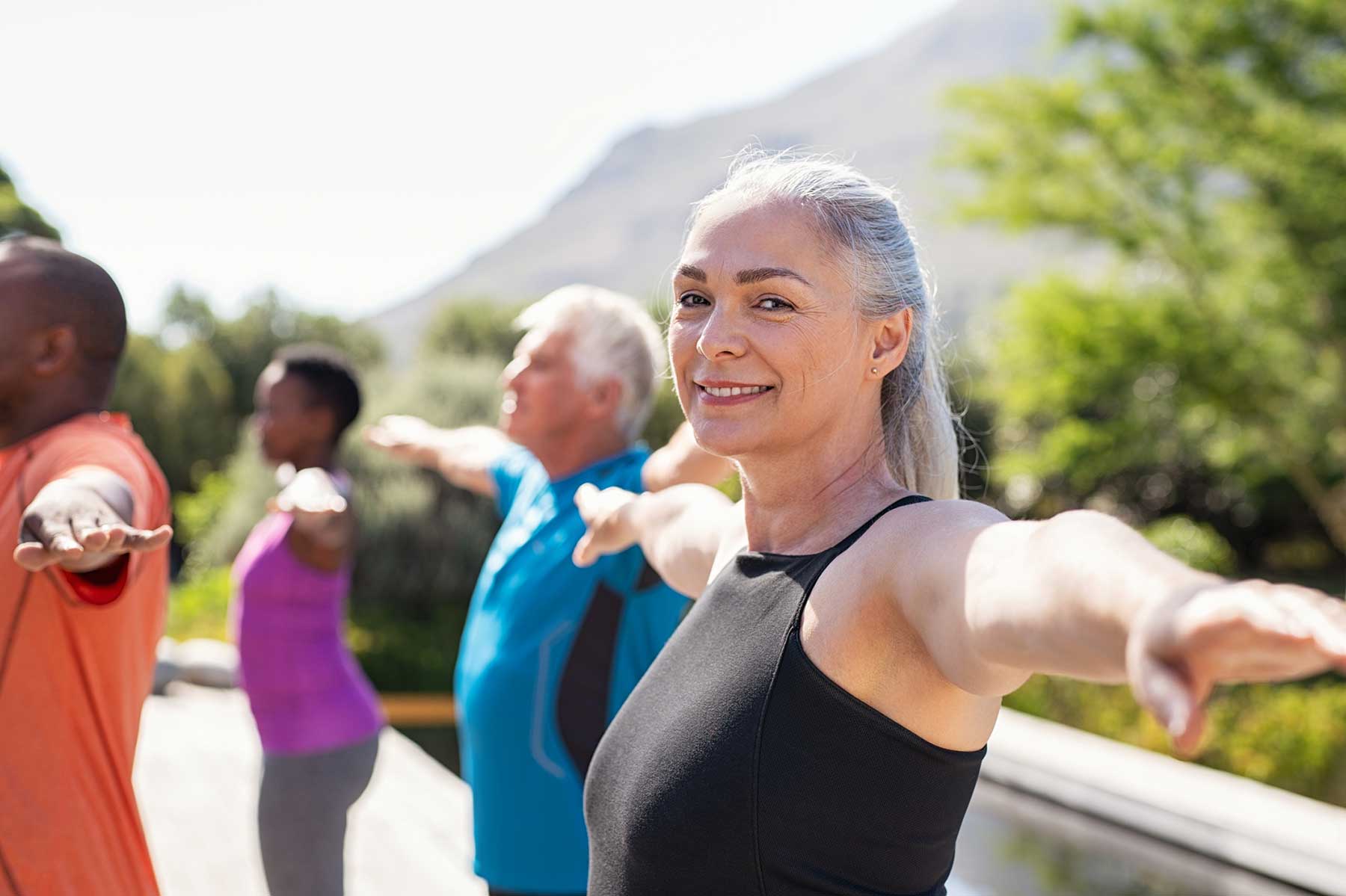 Woman with hearing loss enjoying an exercise class outdoors.