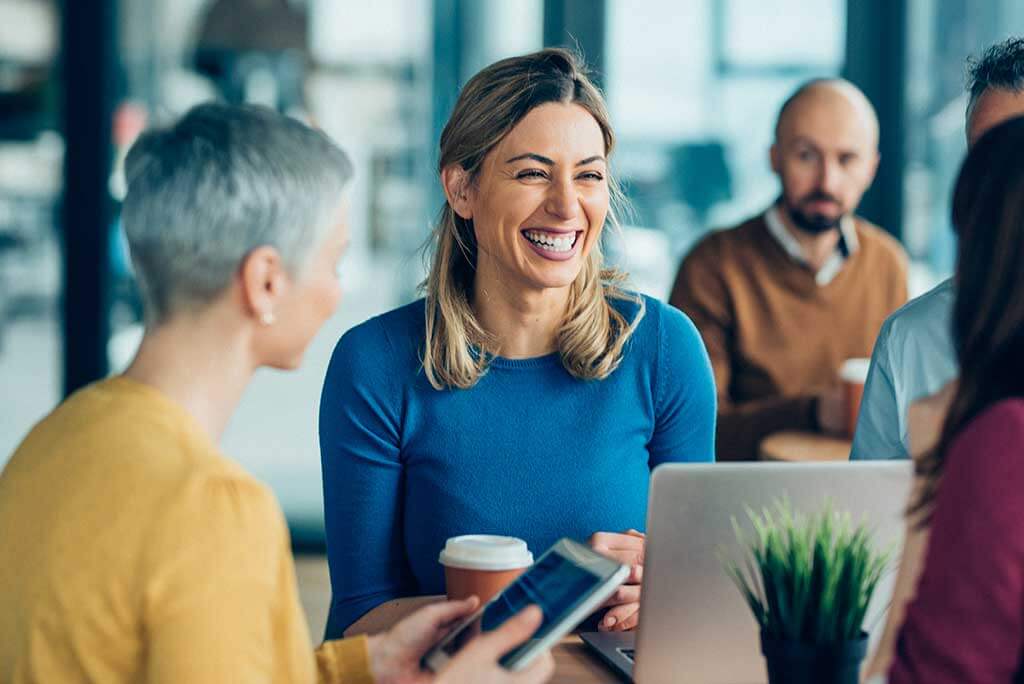 A woman with hearing loss laughing in a business setting.